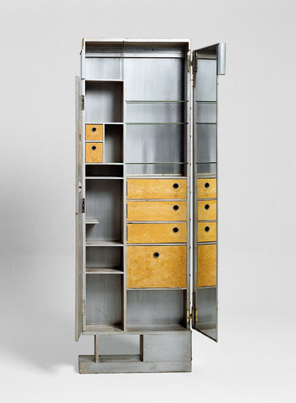 Tall metal storage cabinet. The doors are open to show the interior shelves made out of metal, glass, and cork. The inside of the right door is mirrored.