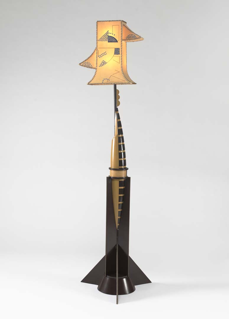 Installation image of a floor lamp with a stylized rocket-shaped stand and geometrically patterned shade.