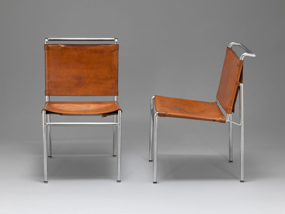 Installation image of two identical chairs made from tanned leather on chromed metal frames.