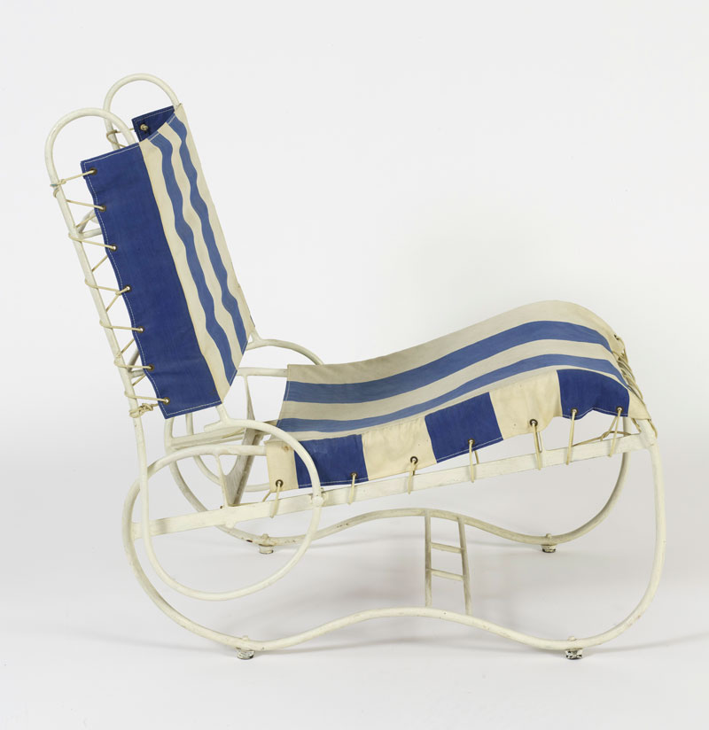 Installation image of a deck chair with blue and white striped fabric stretched across a white metal frame.