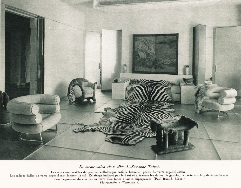 Interior view of a living room with rounded armchairs and zebra hide rugs.
