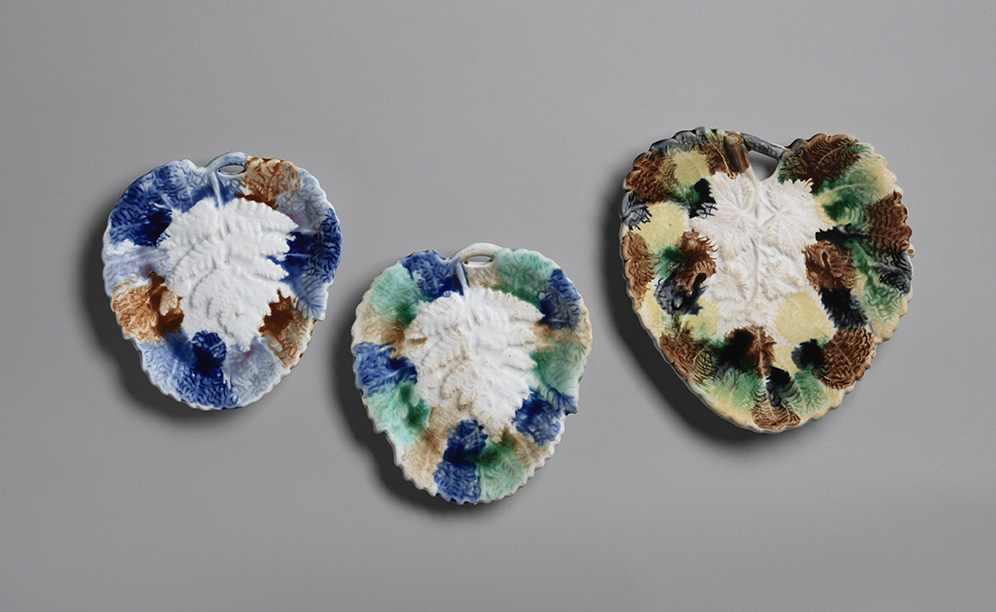 Three majolica plates with three-dimensional molded fern motifs. White centers with various spots of brown, blue, green, and yellow.