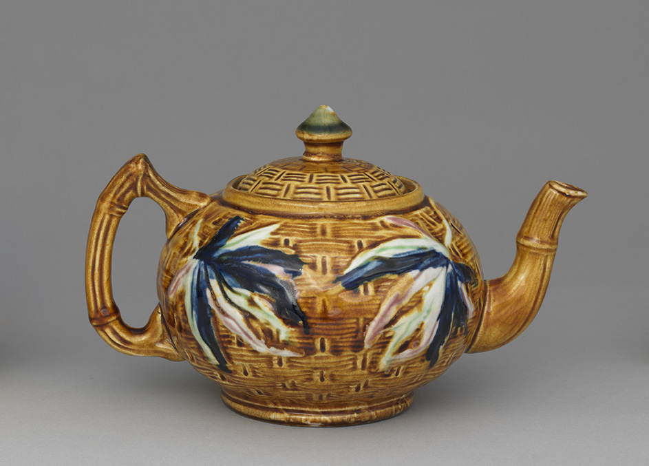Majolica bamboo teapot with brown woven-textured ground, green lid finial, and blue, red, and green bamboo leaves.