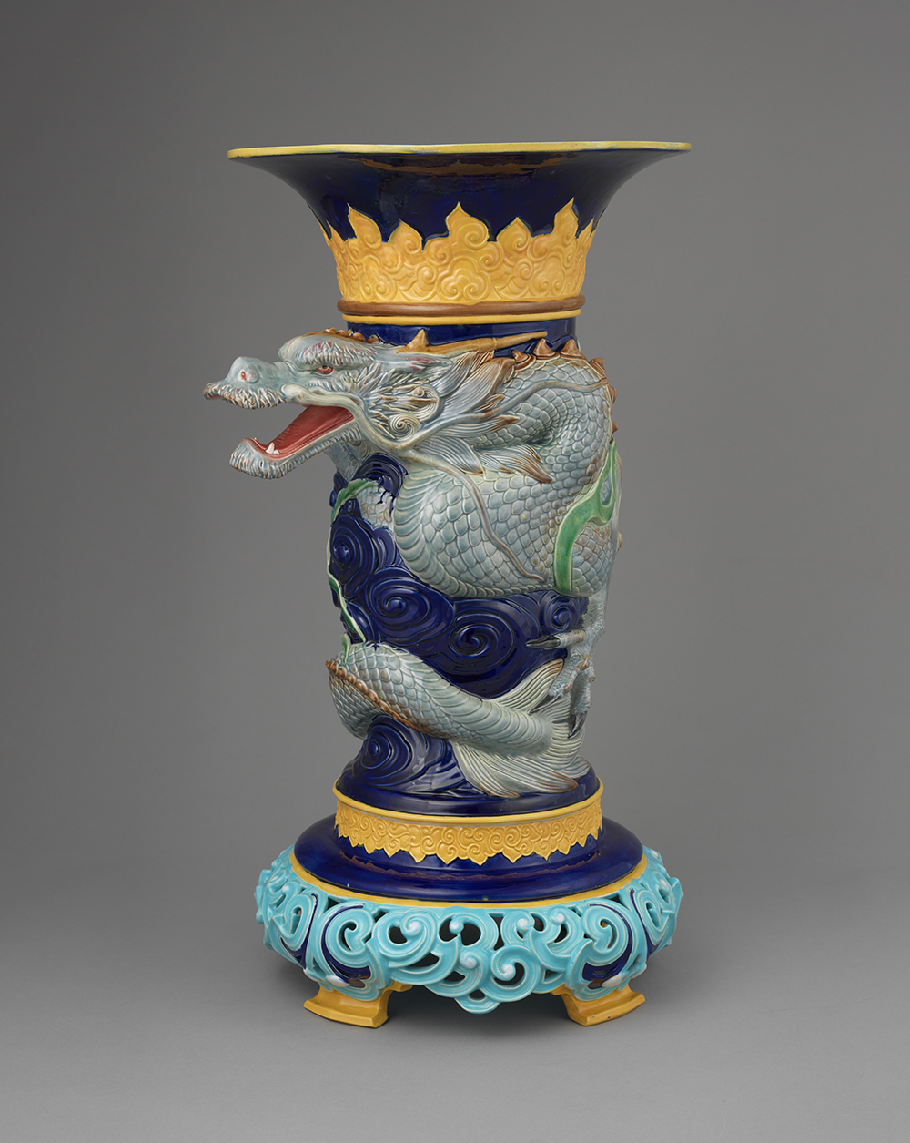 Majolica dark blue ground dragon vase with jade colored dragon, yellow and turquoise detailing, and openwork base.
