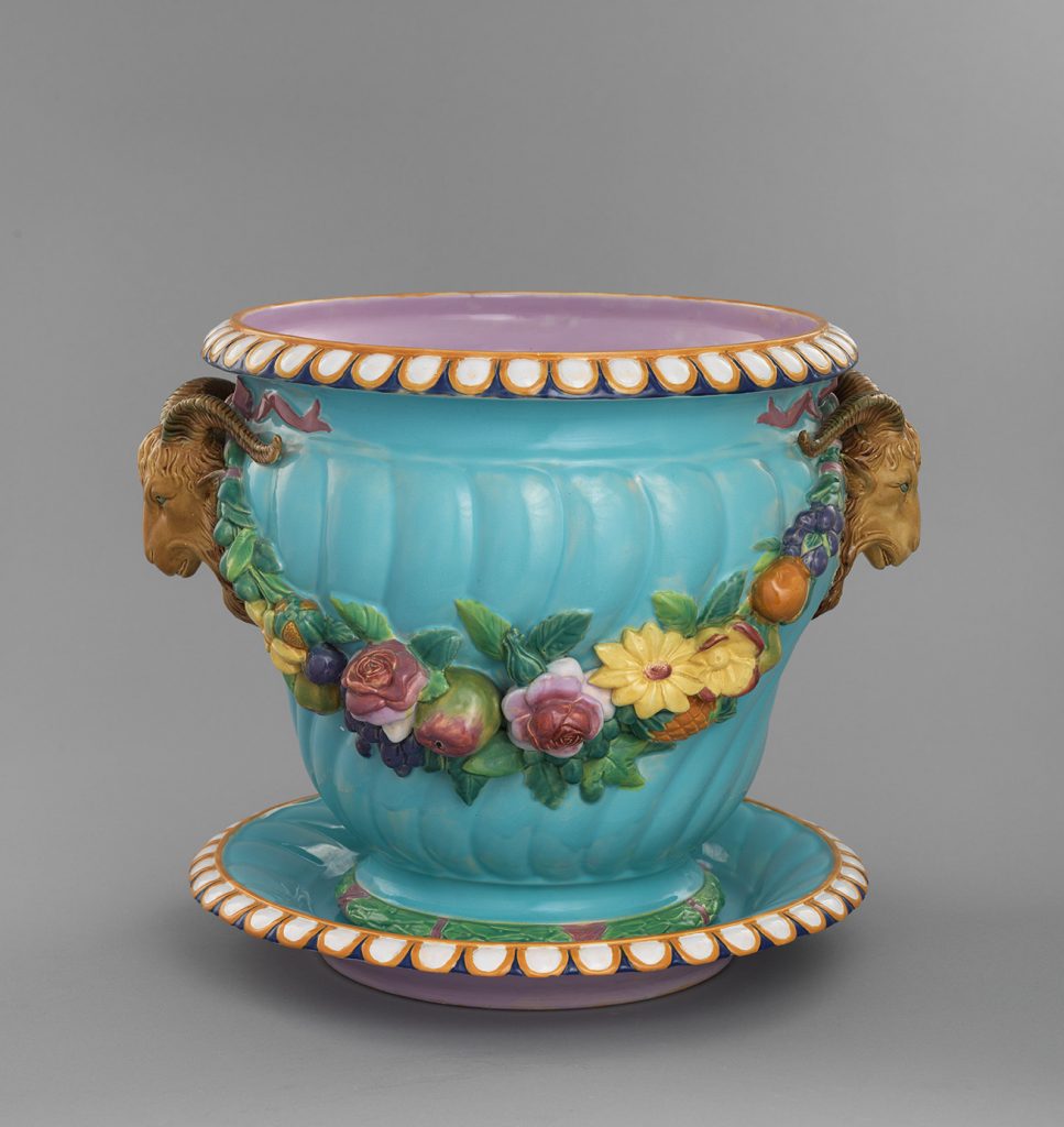 Majolica sky blue garden pot with rams' heads on either side and a festoon of flowers strung between them.