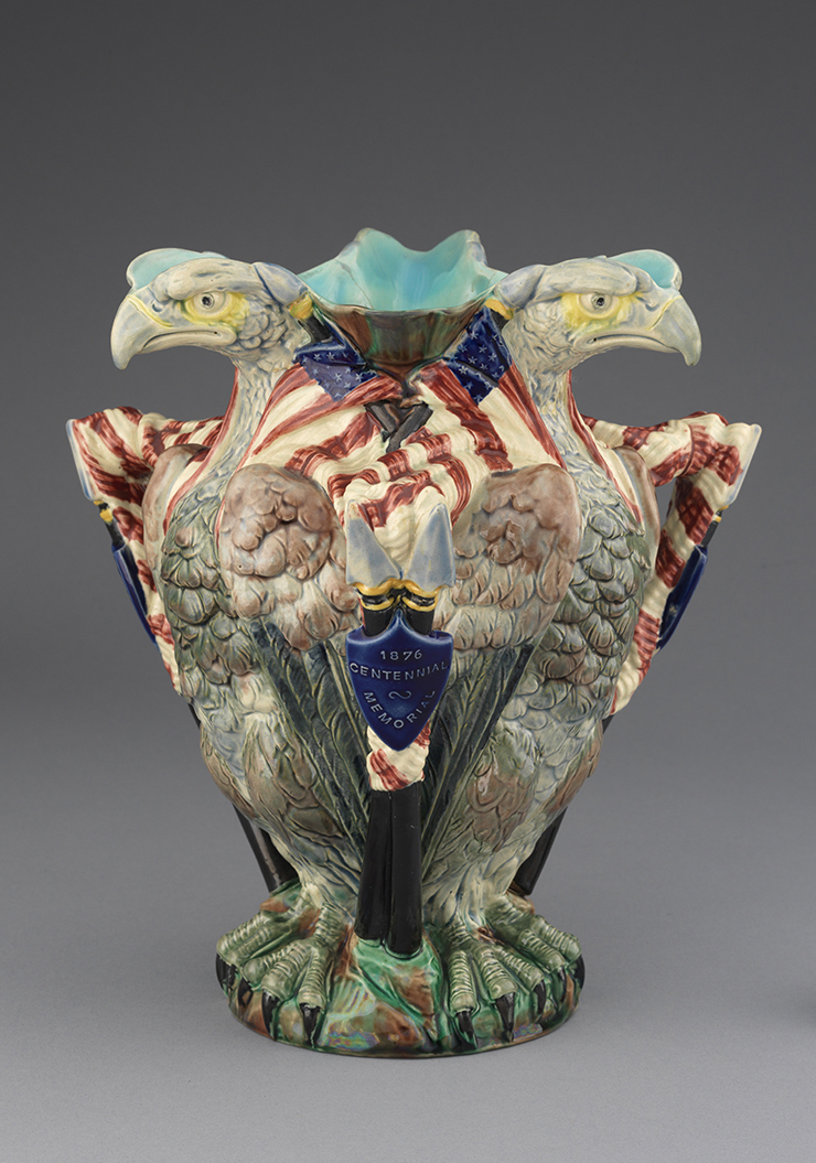 Majolica Centennial pitcher in shape of three eagles with American flags. Color palette of red, white, blue, green, yellow, and brown.