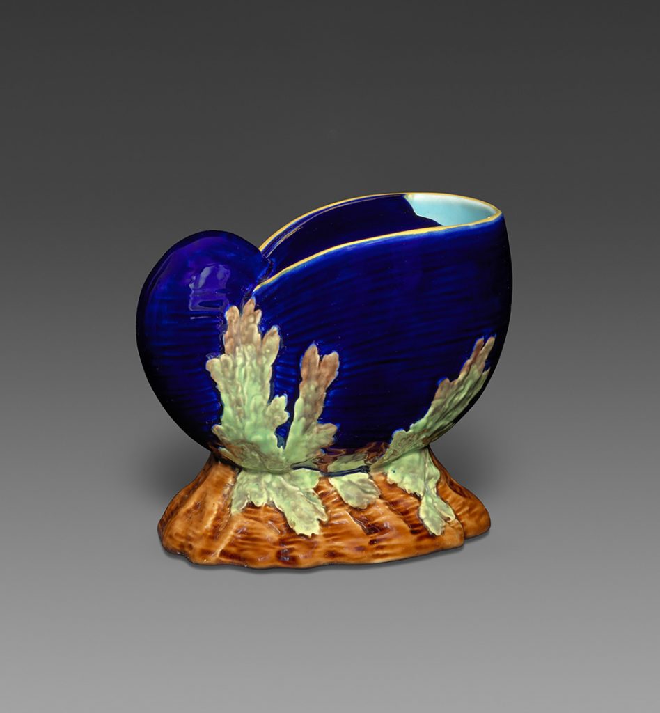 Majolica nautilus shell spoon warmer in dark blue with brown base and kelp motif in green. Interior dark blue and turquoise.