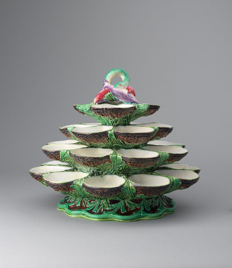Majolica four-tiered oyster stand in green abd brown with green, red, and purple fish finial. Serving bowls shaped like oysters.