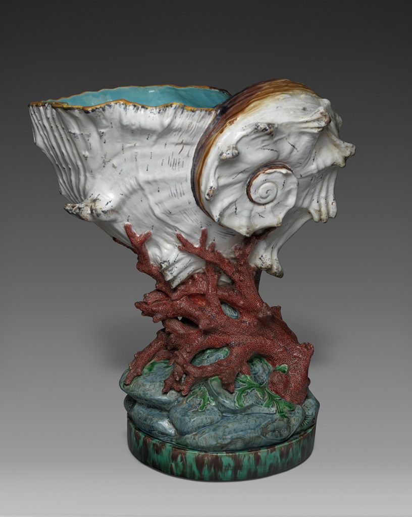 Majolica nautilus shell cup with coral stem and rock base. White shell, red coral, green, blue, and gray base, turquoise interior.