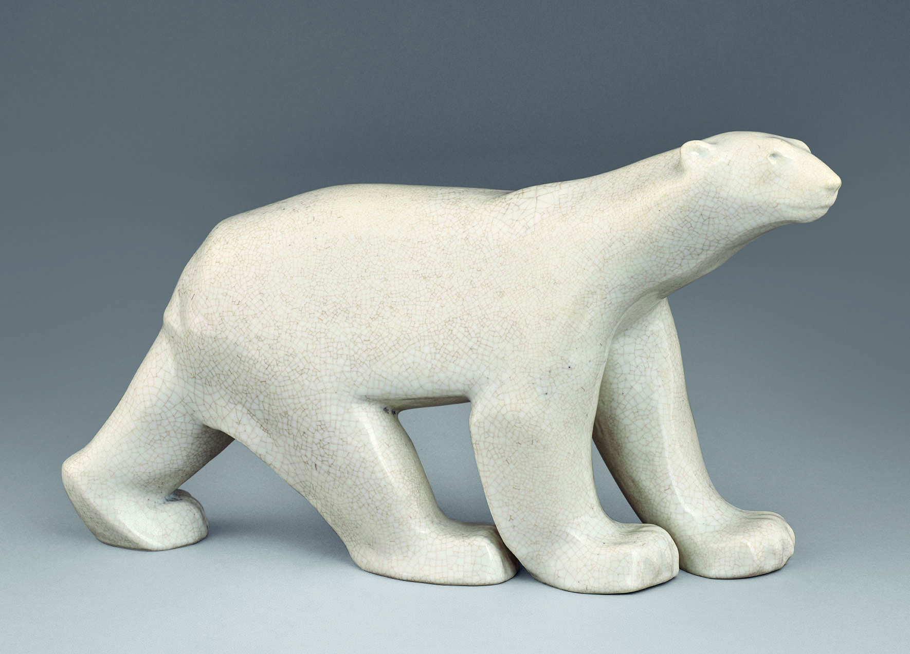 A sleek, smooth, white ceramic sculpture of a polar bear on all fours. The bear is depicted with simplified, rounded features, a subtle texture on its surface, and a slight tilt of its head, creating an elegant and modern interpretation of the animal.