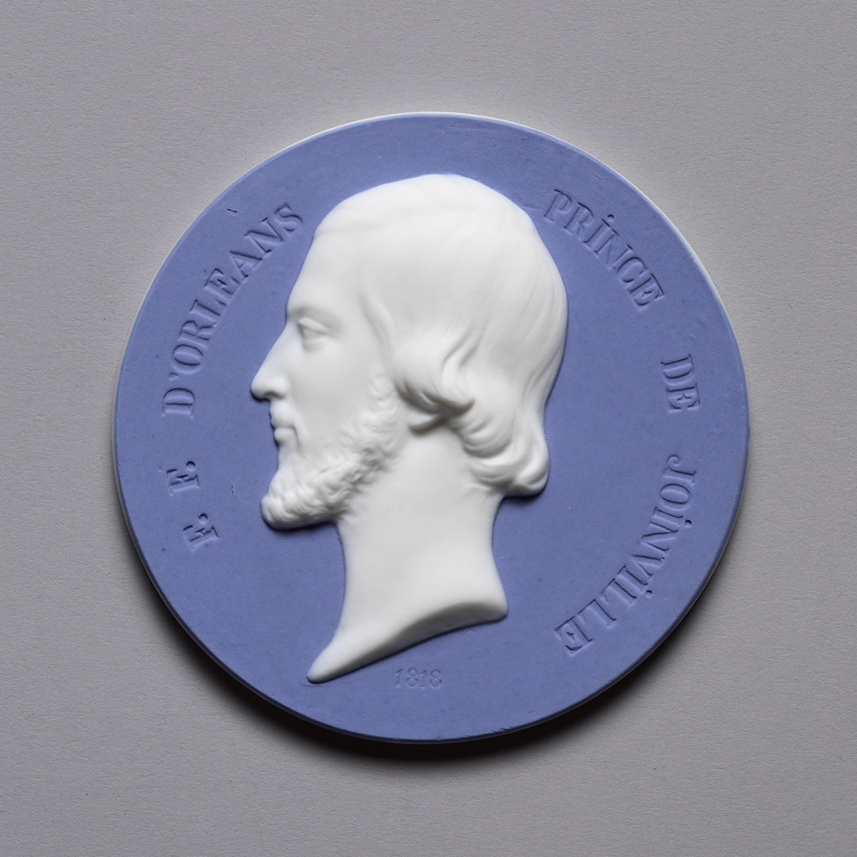 A circular medallion depicting a side profile of a bearded man in white relief against a blue background. The inscription reads "F. E. D'Orleans Prince De Joinville 1829.