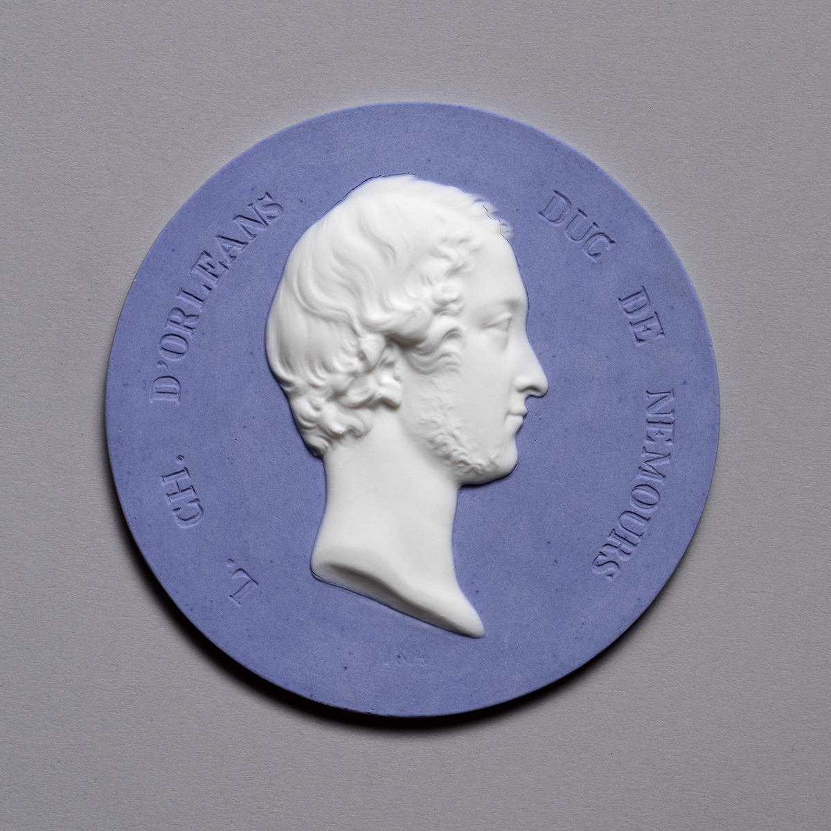 A circular medallion features a white profile relief of a bearded man with short hair against a pale blue background. The lettering reads "CH. D'ORLEANS DUC DE NEMOURS" around the edge.