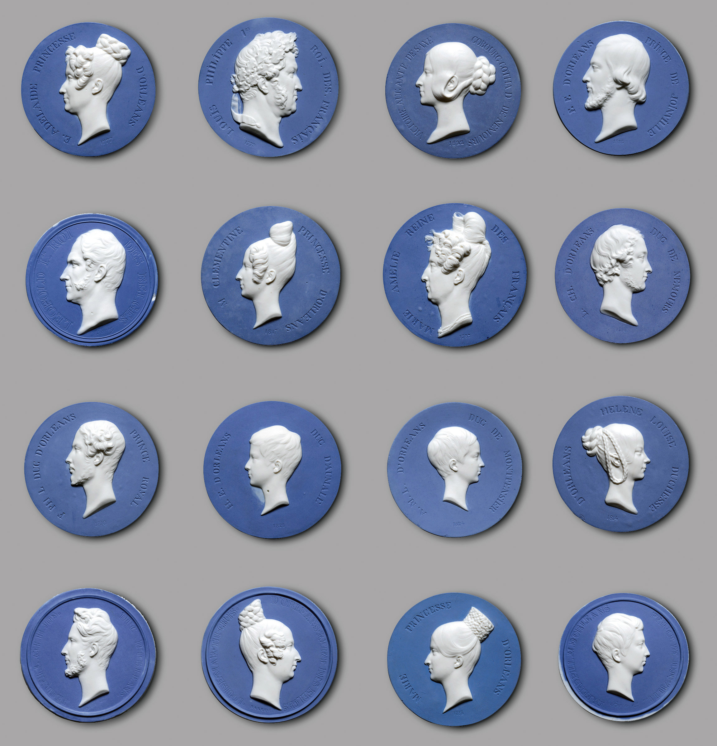 A grid of 16 blue coins or medallions on a grey background. Each medallion features a white relief profile portrait of various individuals, both male and female, with detailed hairstyles and attire, set against the uniform blue backdrop.