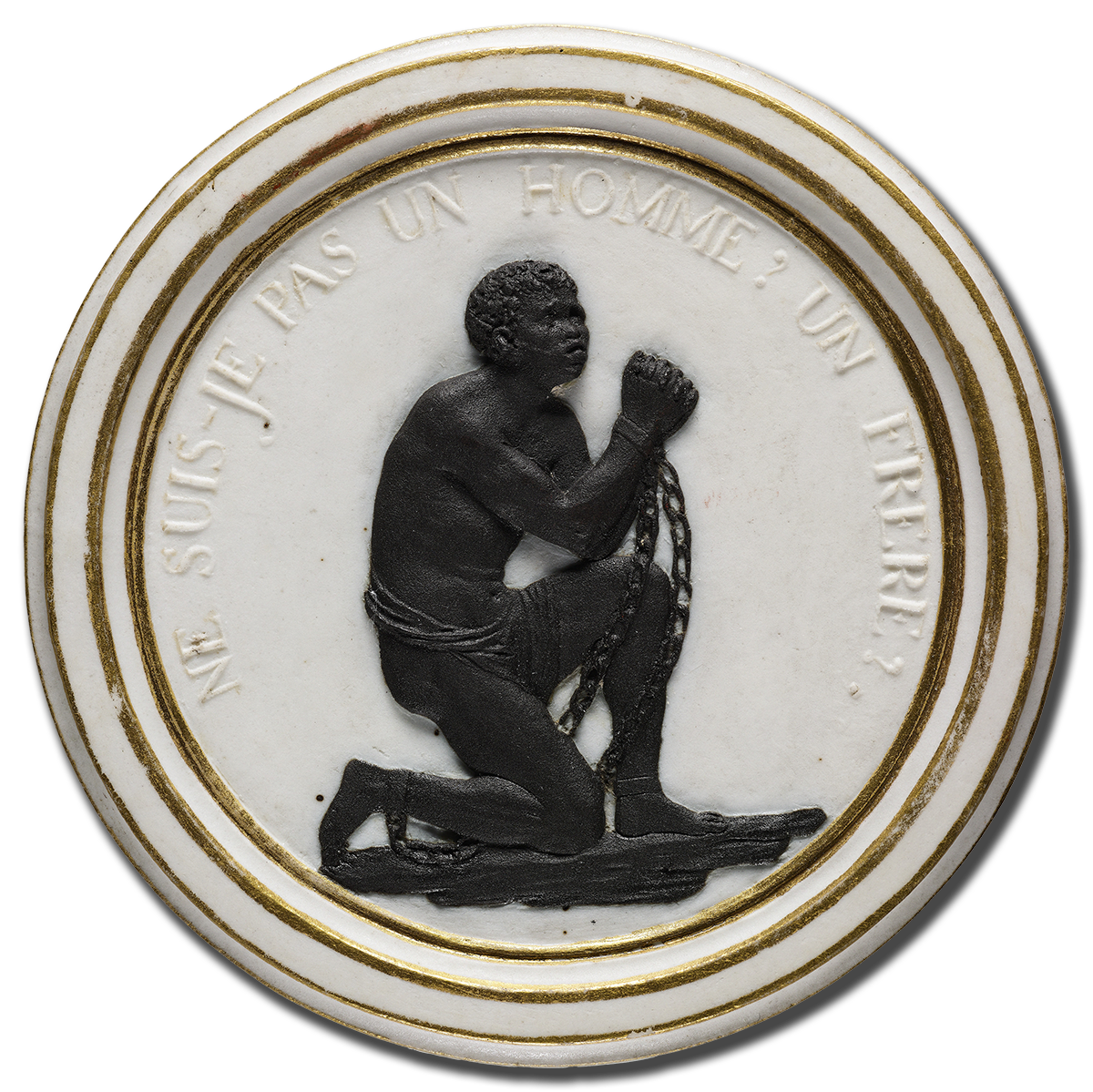 A circular medallion features an embossed image of a black man kneeling, with shackled wrists raised as if in prayer or plea. The edge of the medallion is gold-rimmed, and inscribed above the figure are the words "NE SUIS-JE PAS UN HOMME ET UN FRÈRE?.