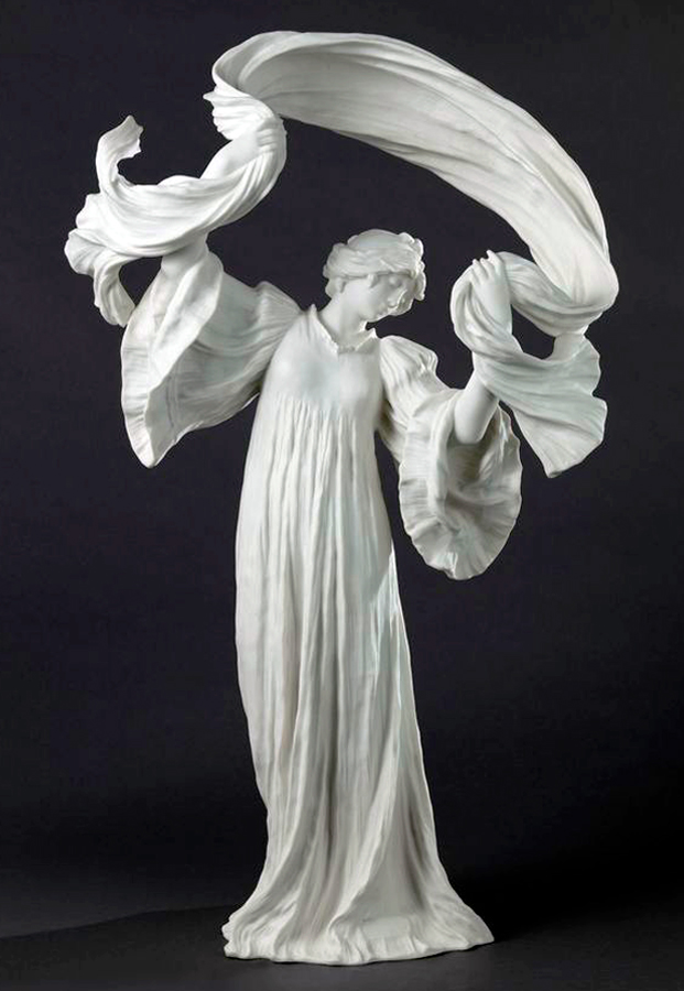 A flowing white sculpture of a figure in a long robe, with arms raised holding billowing fabric above their head. The piece conveys movement and grace against a dark background.