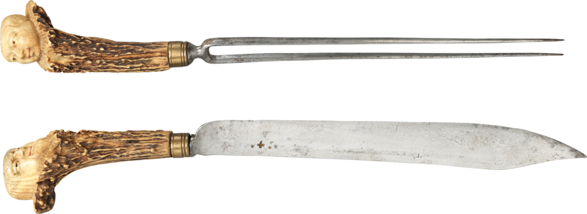 A knife and two-pronged fork, both featuring an intricately carved ivory handle with a sculpted face at the top.