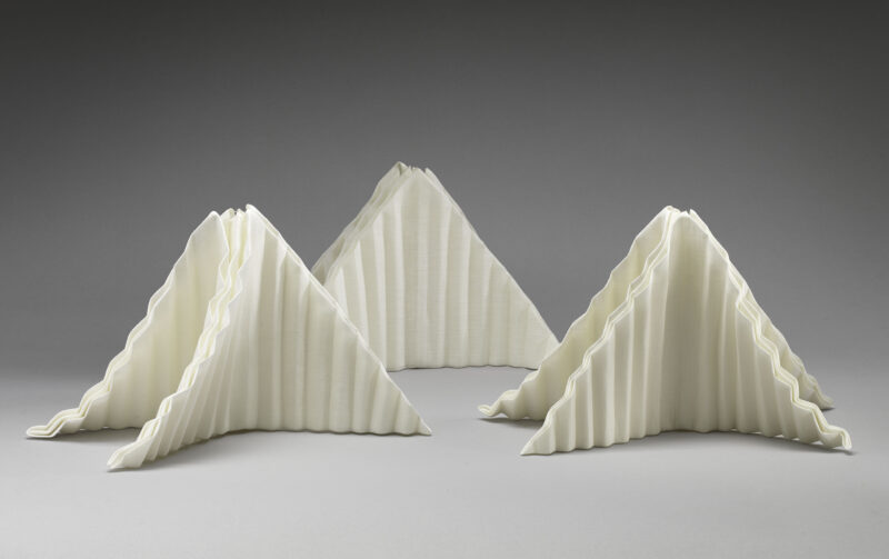 Three napkin sculptures folded to represent mountain peaks.