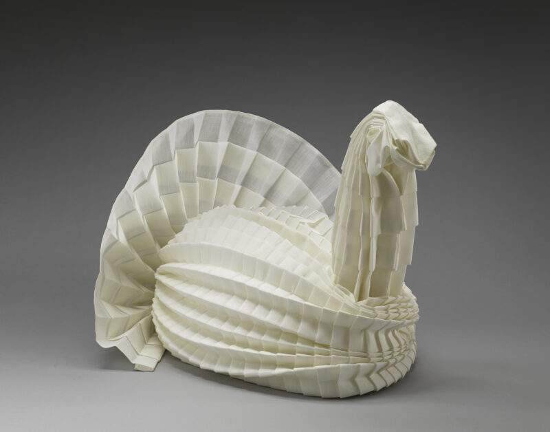 An intricate napkin sculpture depicting a turkey with a fanned out tail.