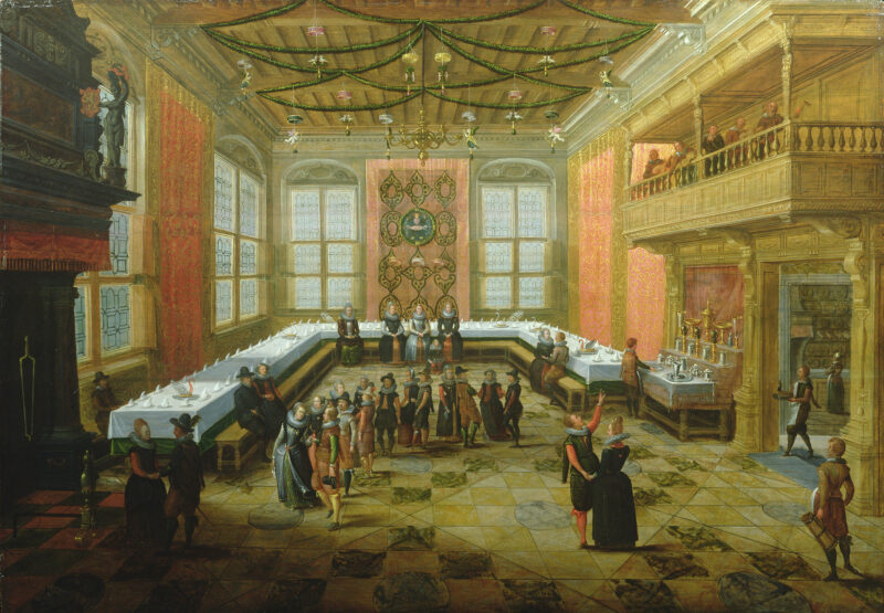 A detailed painting of a grand hall with large windows set for a feast. A large "U" shaped table is covered with white linen cloth and is topped by place settings for guests. The napkin on each plate is folded to resemble a wave and several swan figures are located in the middle of the table. Some guests are seated at the table while others converse around the room. On a balcony several musicians play for the guests. Workers are also seen preparing the room for the upcoming meal.