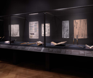 Detail of the Tools of the Trade section of the "Staging the Table in Europe 1500-1800" exhibition installation case featuring various carving tools as well as illustrations and open books with similar tools.