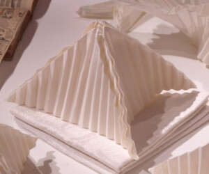 Detail from the "Staging the Table in Europe 1500-1800" exhibition featuring a napkin folded in the shape of a pyramid sitting atop several other napkins folded into squares.