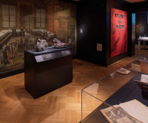 Detail of the "Staging the Table in Europe 1500-1800" exhibition installation featuring a case with a turkey and a boar's head tureen in front of a large scale image of a period dining hall.